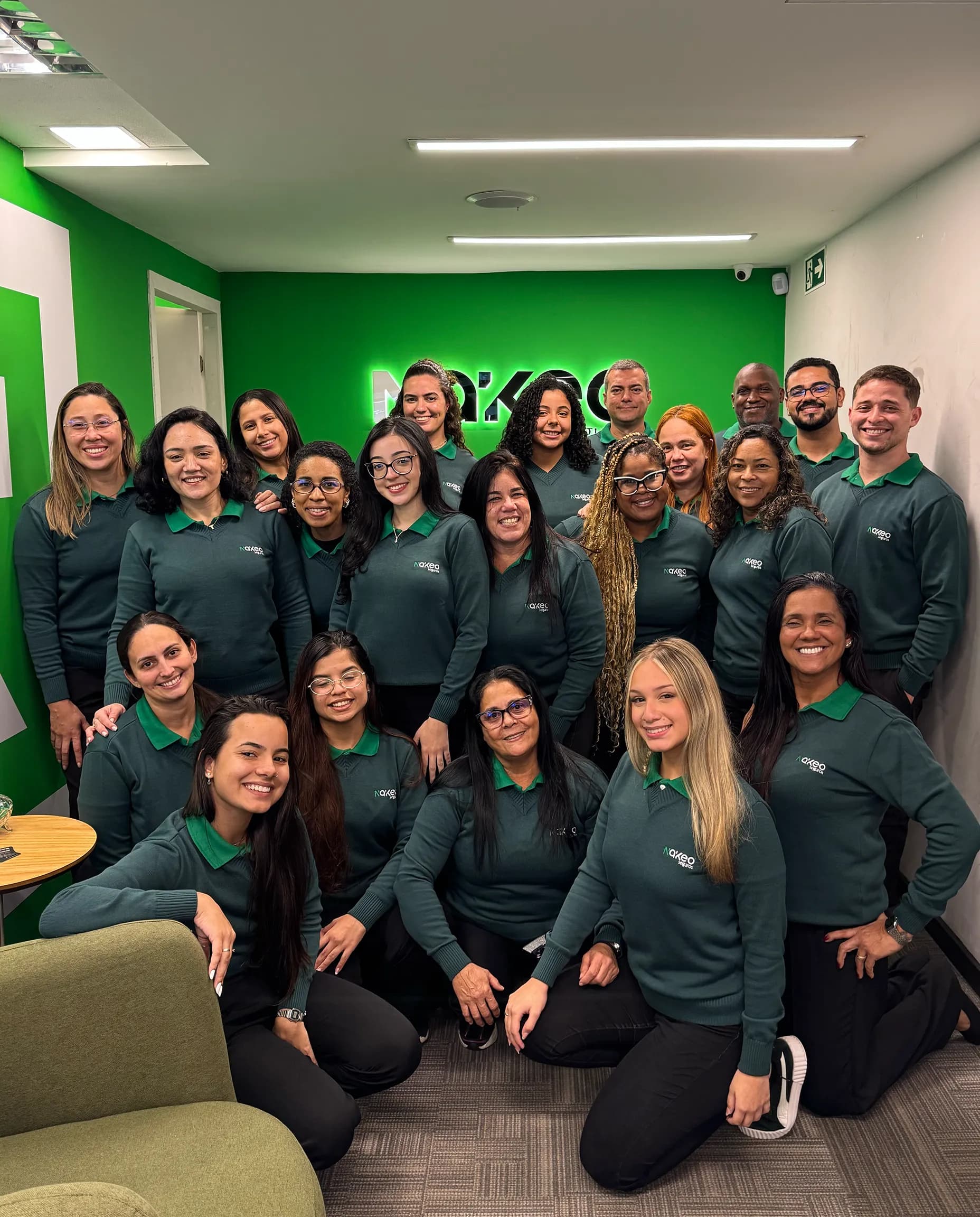 Equipe Nákeo reunida e sorrindo, com a logo da marca ao fundo